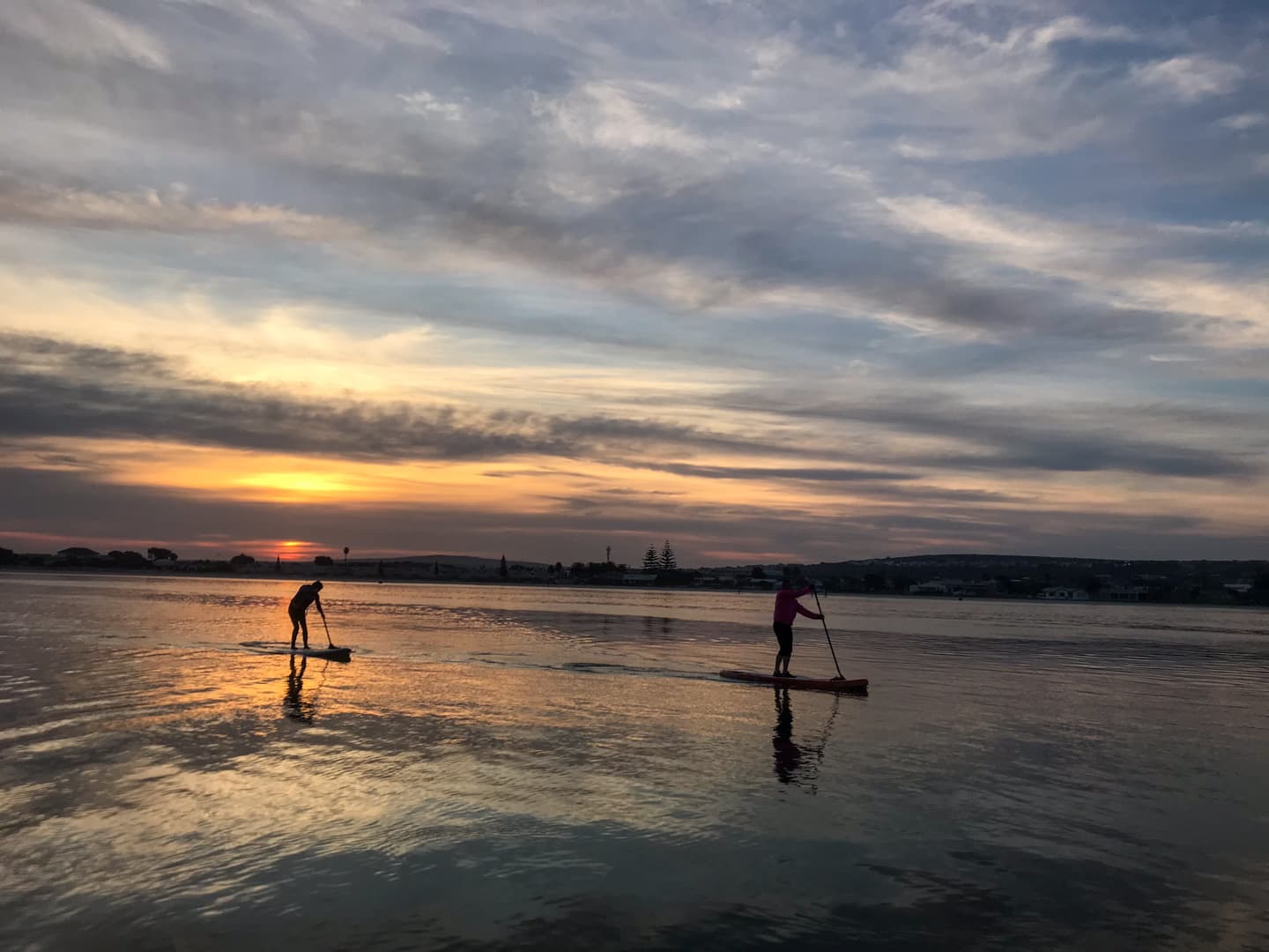 Silhouette of paddleboarders on Langebaan Lagoon at sunset